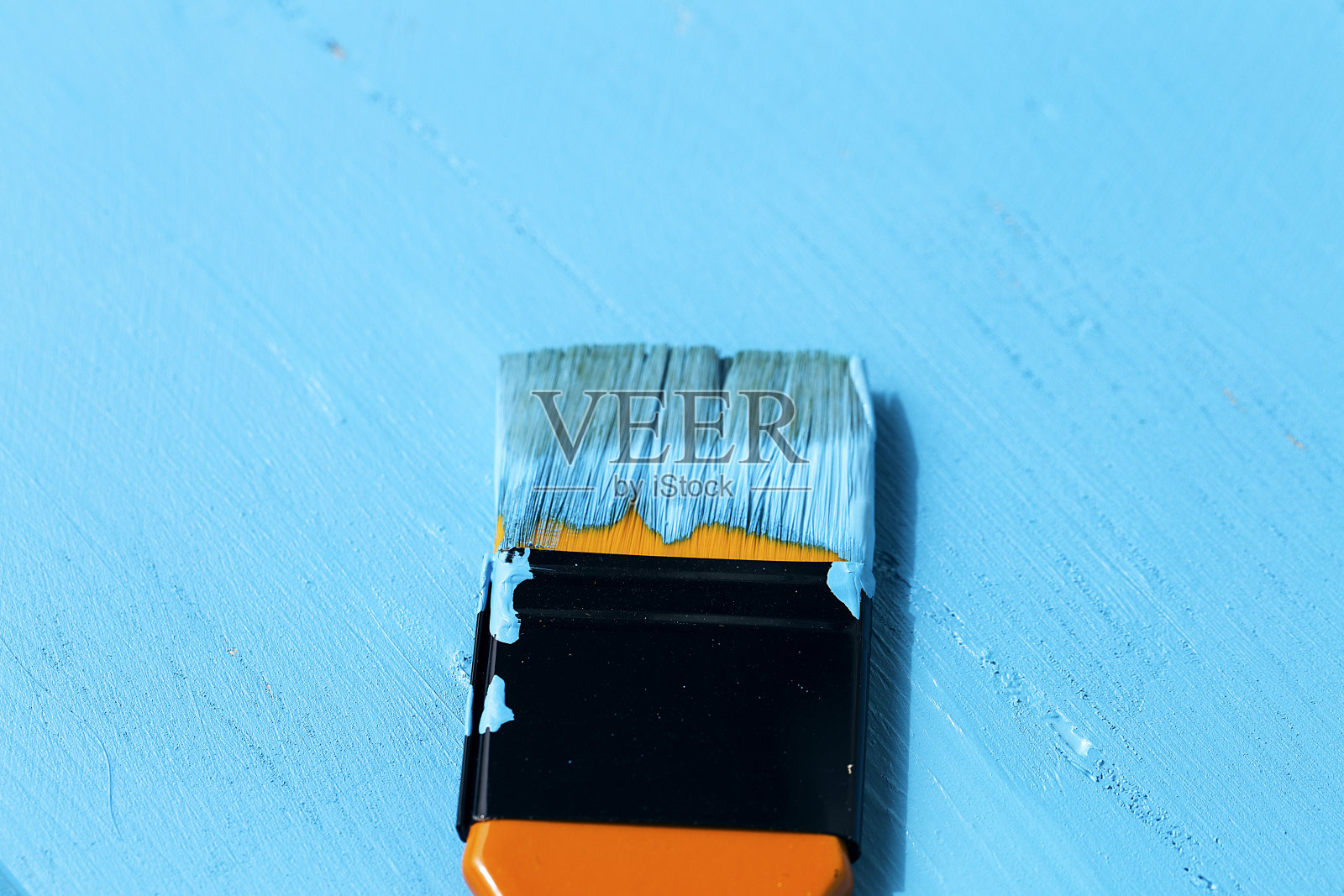 用橙色的油漆刷蘸上蓝色的油漆照片摄影图片