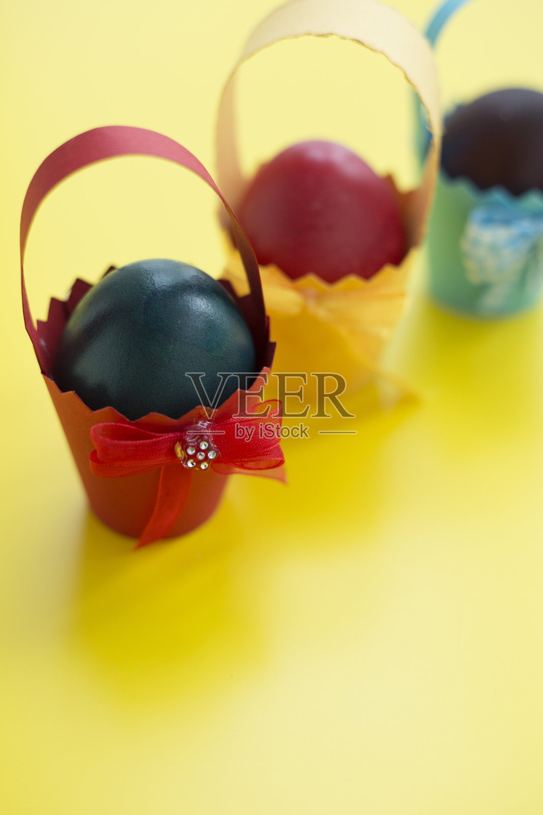 黄色背景纸杯里的五颜六色的东方彩蛋。有选择性的重点照片摄影图片