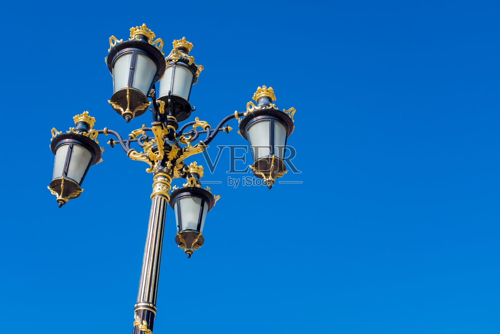 西班牙马德里皇家宫殿。蓝色天空上奢华的金色街道照明系统照片摄影图片