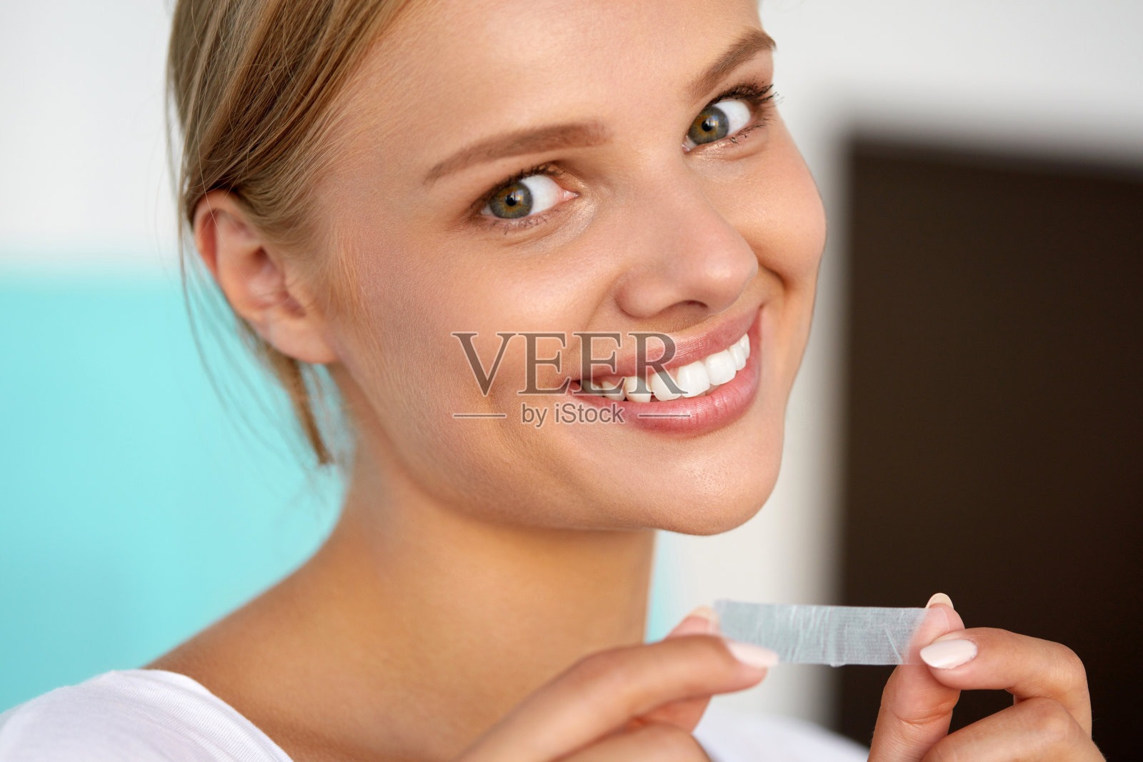 女人使用牙齿美白带美丽的白色微笑照片摄影图片