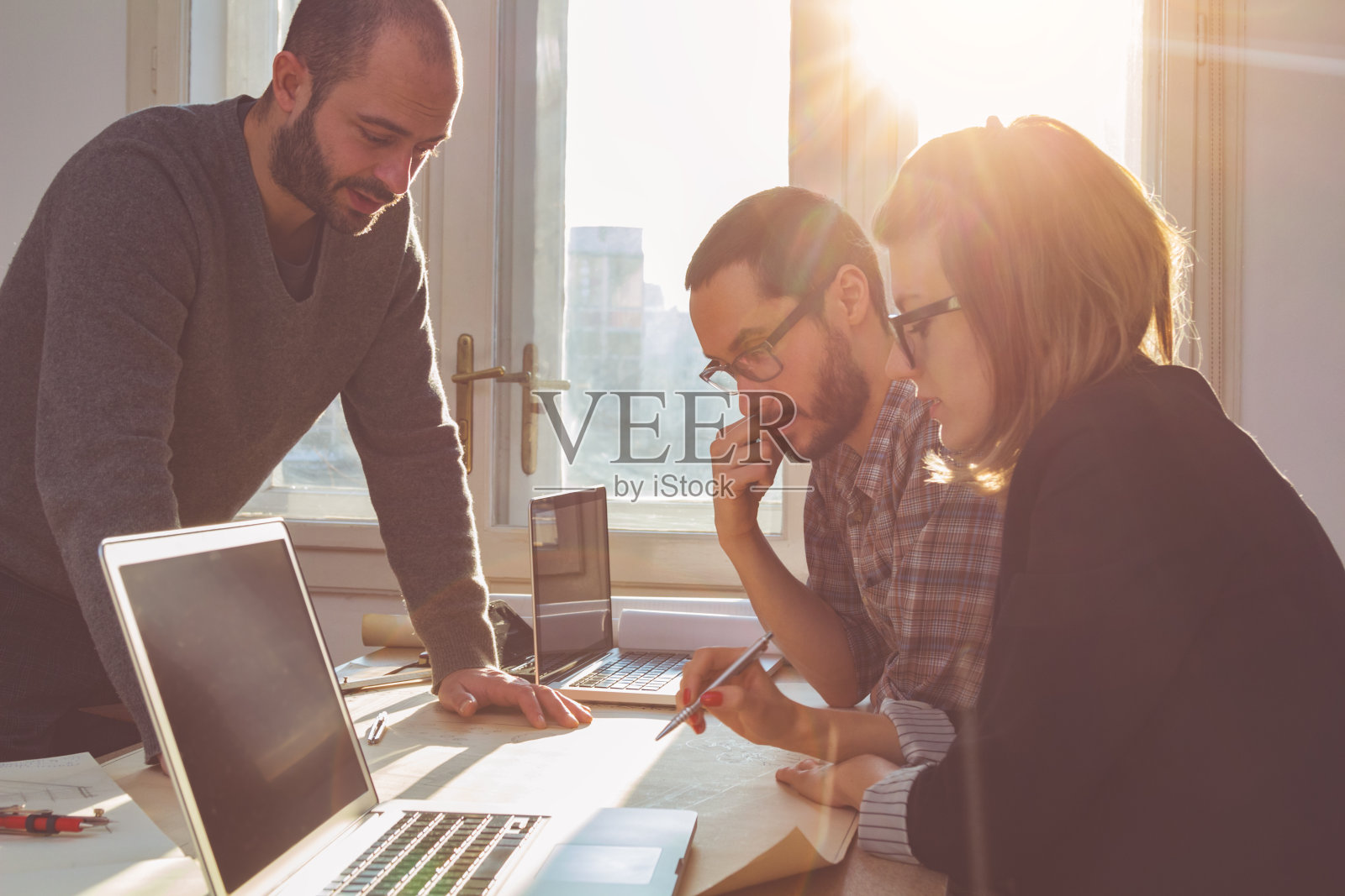 一群年轻建筑师在阳光明媚的办公室里。照片摄影图片