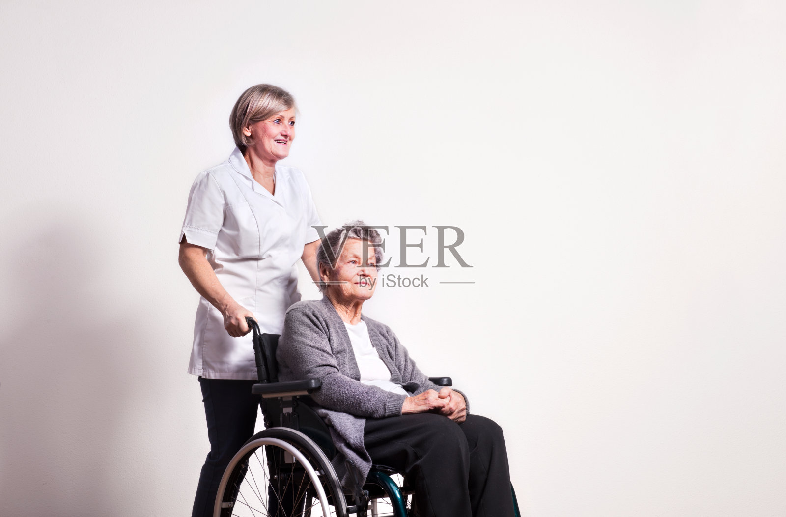 坐在轮椅上的年长妇女与一名护士的棚拍肖像照片摄影图片