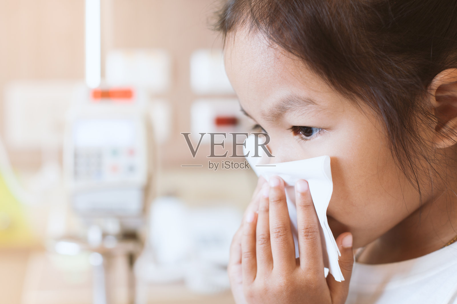 生病的亚洲小女孩在医院用纸巾擦鼻子照片摄影图片