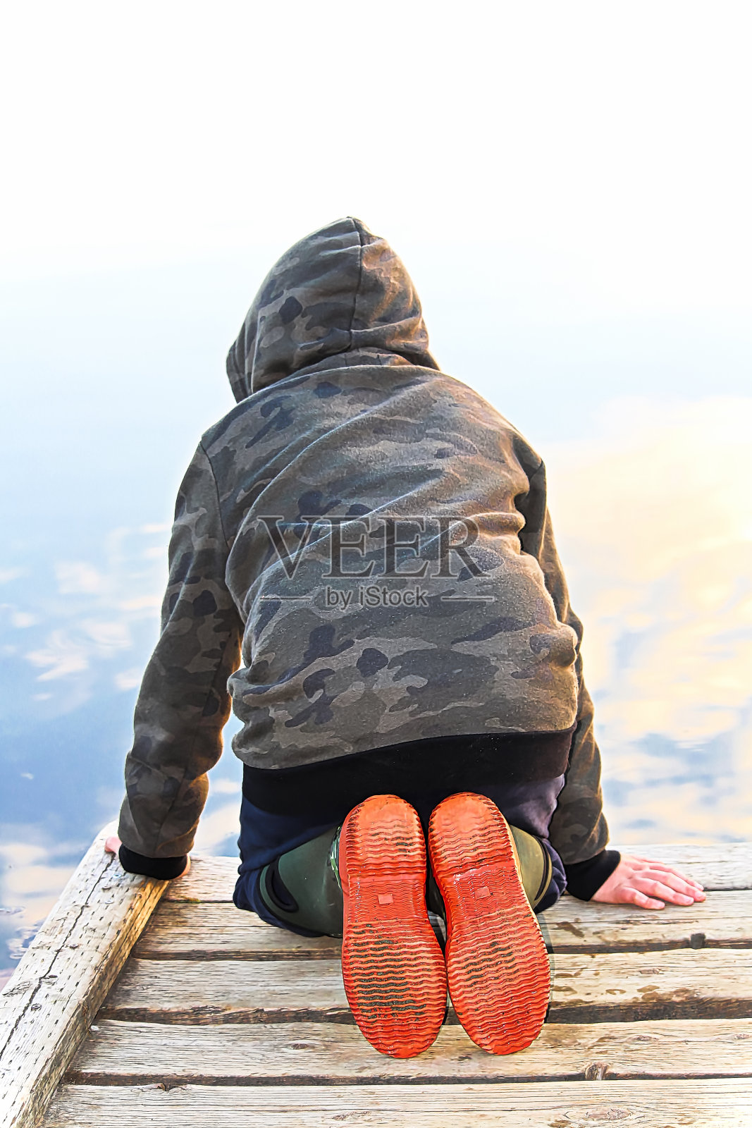 一个孩子看着水和镜子反射的天空照片摄影图片