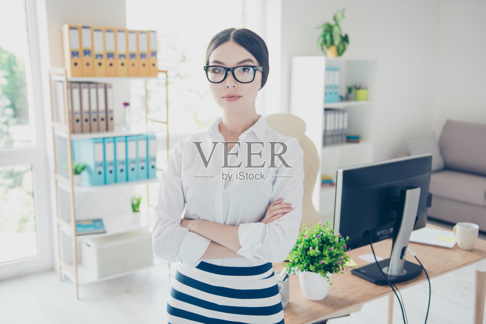 成功的概念。肖像严肃的年轻亚洲商务女士在眼镜和马尾辫，站在她的办公室严格时尚的服装，黑色眼镜照片摄影图片