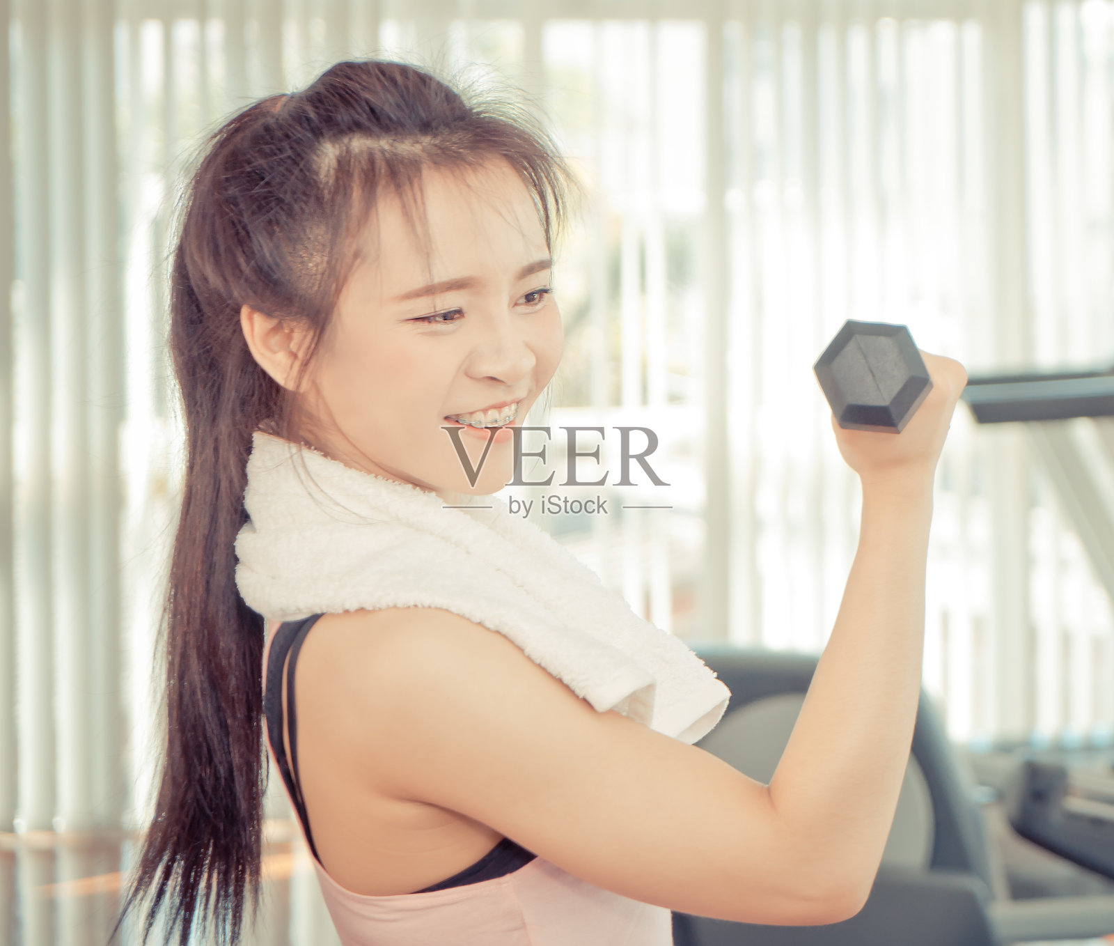 一个女人在健身俱乐部拿着哑铃的肖像照片摄影图片