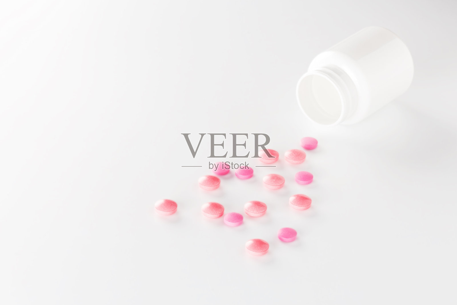 一堆红色的药丸和塑料白色的瓶子。药丸在白色的背景。保健和医学的概念。照片摄影图片