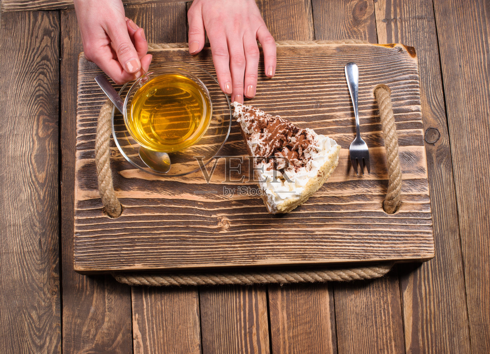 手拿着茶和蛋糕放在木桌上照片摄影图片