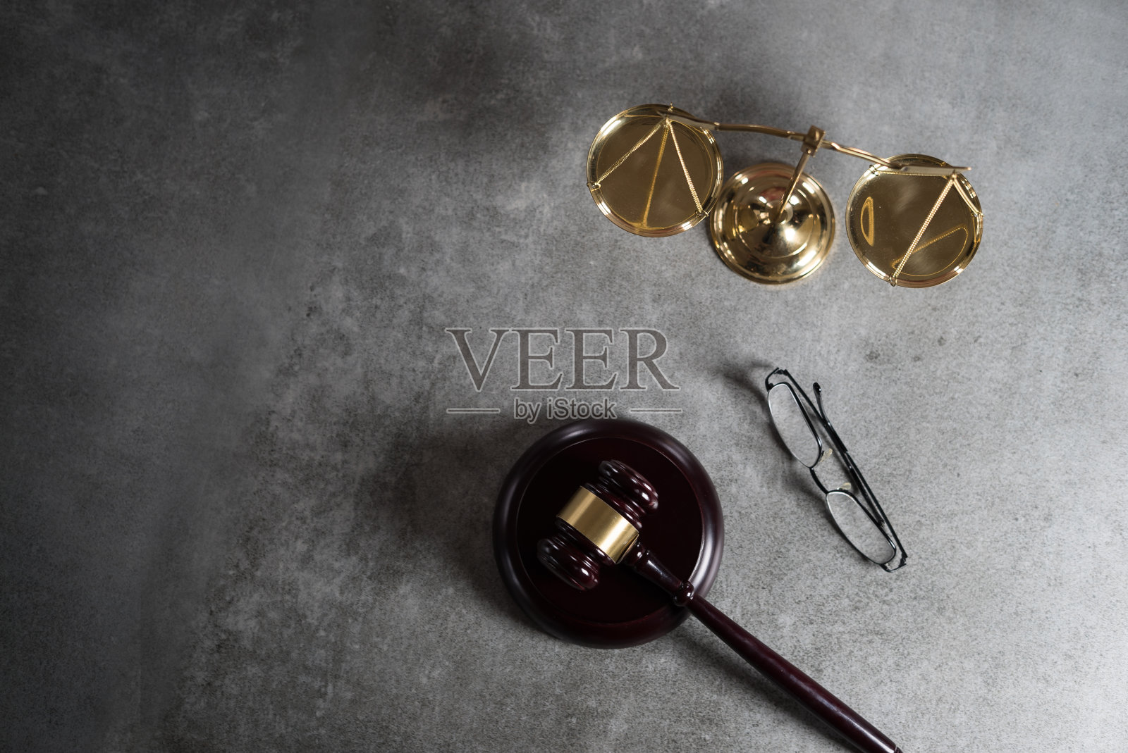 法律与正义概念：法官木槌、眼镜、正义天平，灰色石材背景，带排版位置的法庭主题照片摄影图片