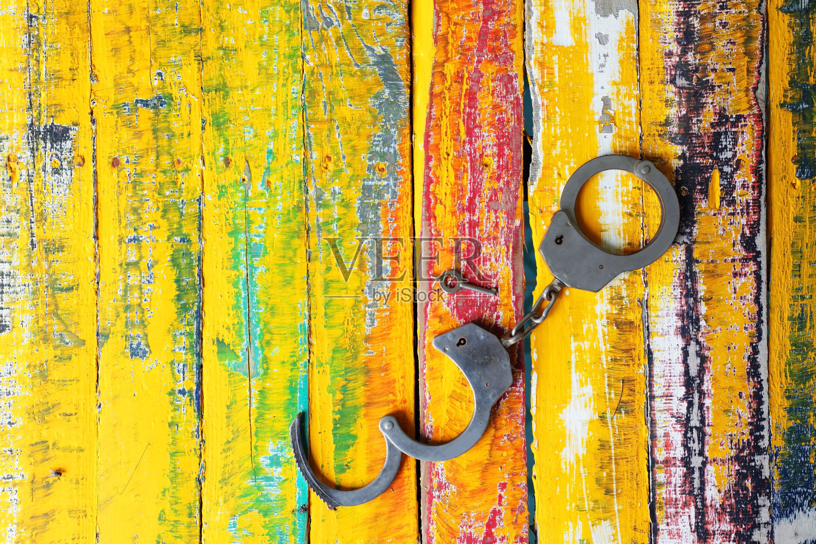 手铐在垃圾彩色木制面板背景。照片摄影图片