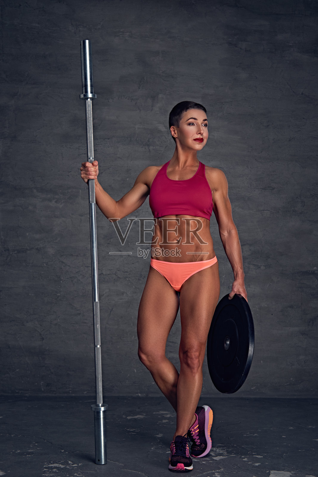 中年妇女举着杠铃。照片摄影图片