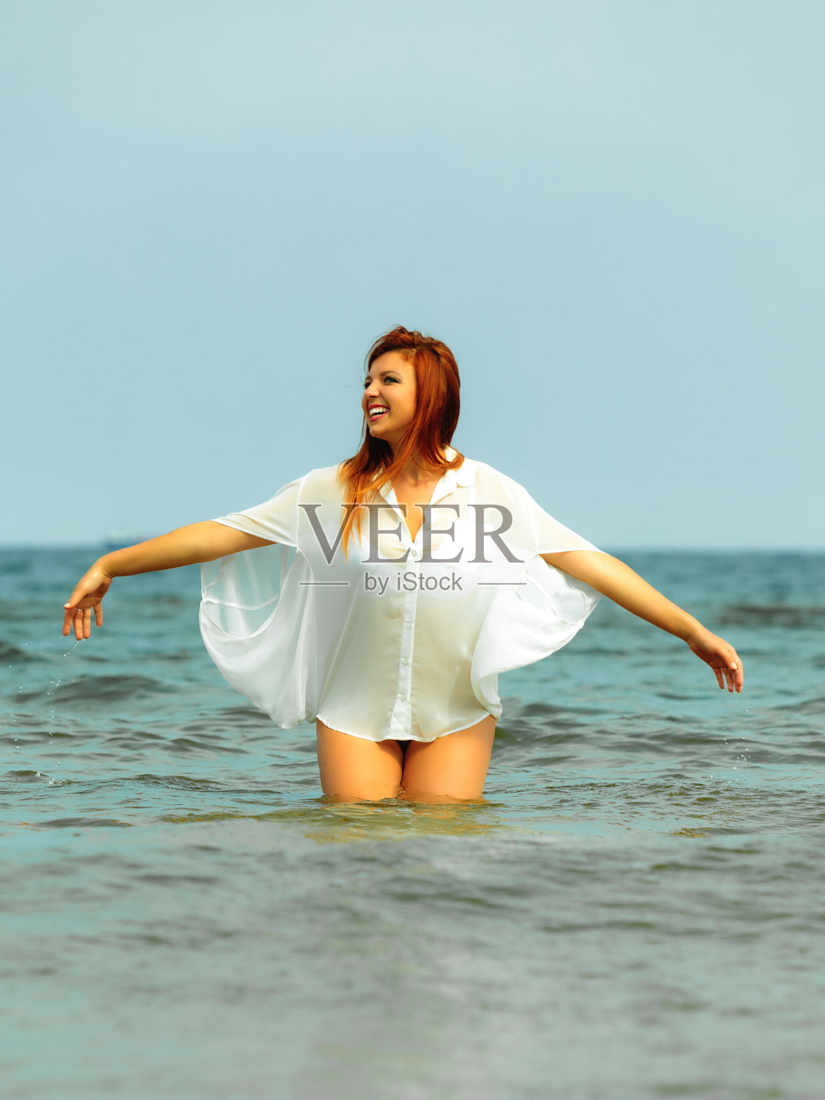 夏天在水里玩的红发女人照片摄影图片