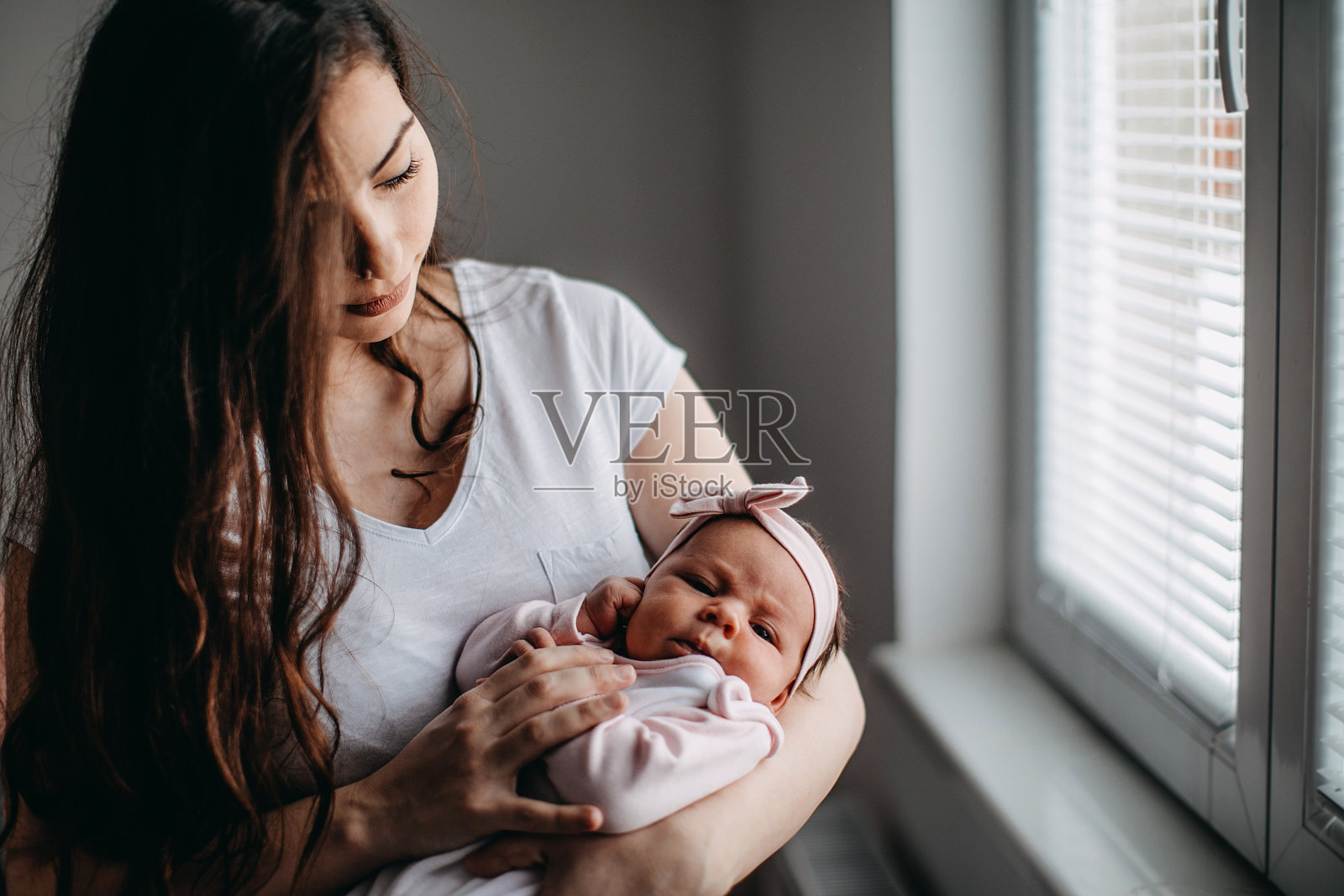 年轻的母亲，抱着她刚出生的女儿在客厅里照片摄影图片