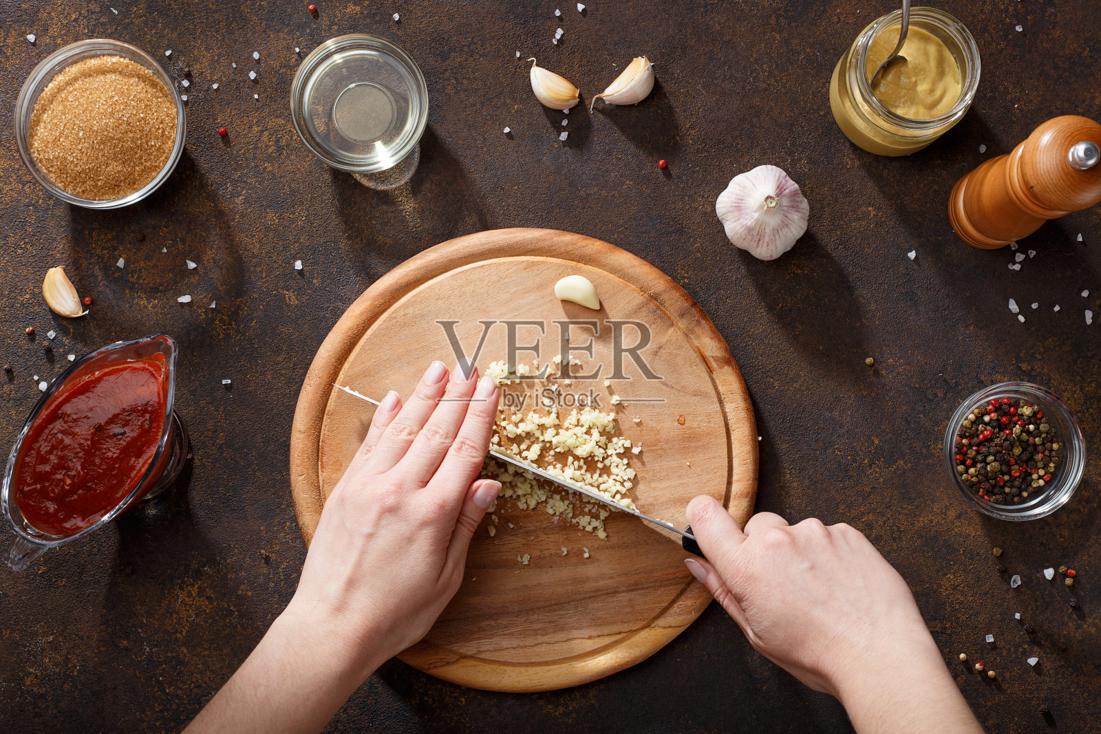 用手切碎的大蒜来烹饪烧烤酱，放在烤鸡翅的木板上。照片摄影图片