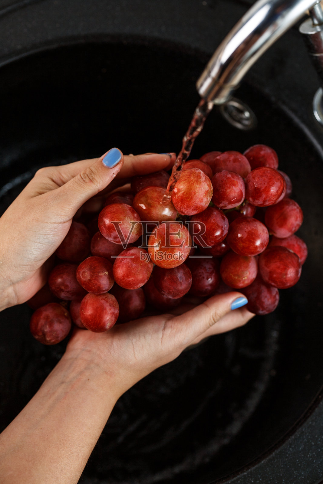 这女孩手里洗着一串红葡萄照片摄影图片