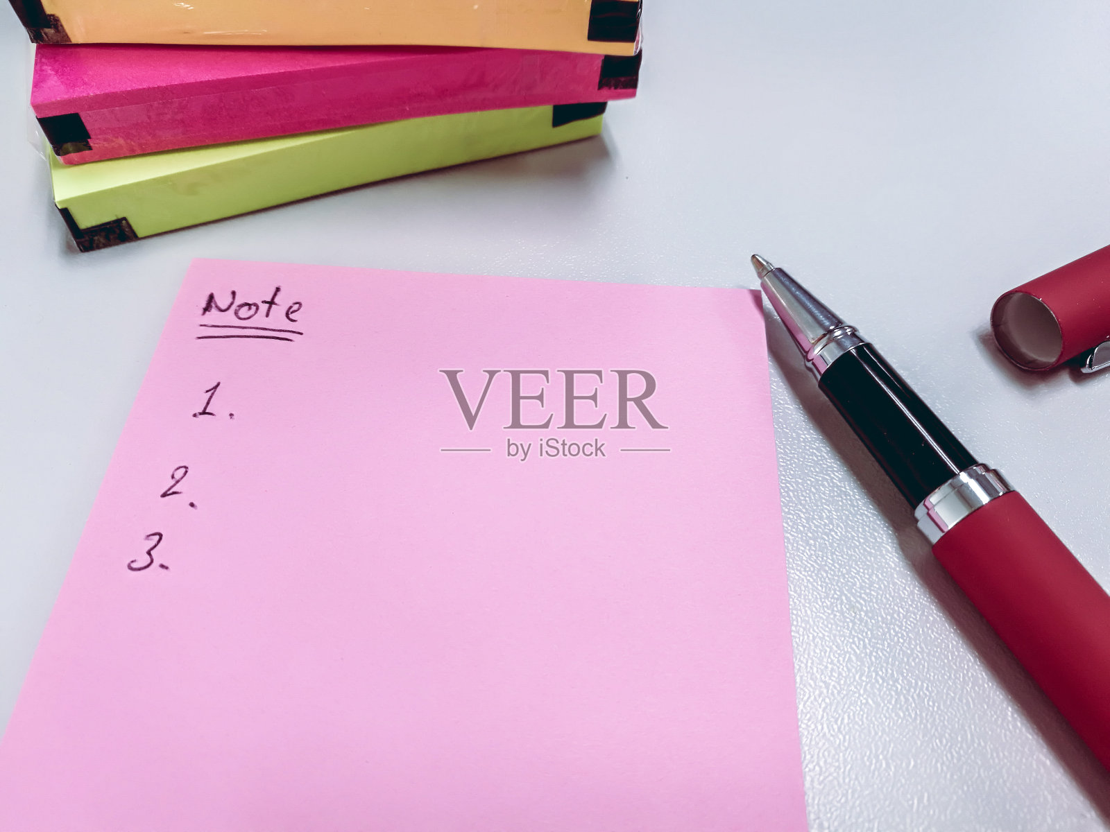 用粉红色的空白纸写便条和物品清单。靠近笔和包的彩色纸条照片摄影图片