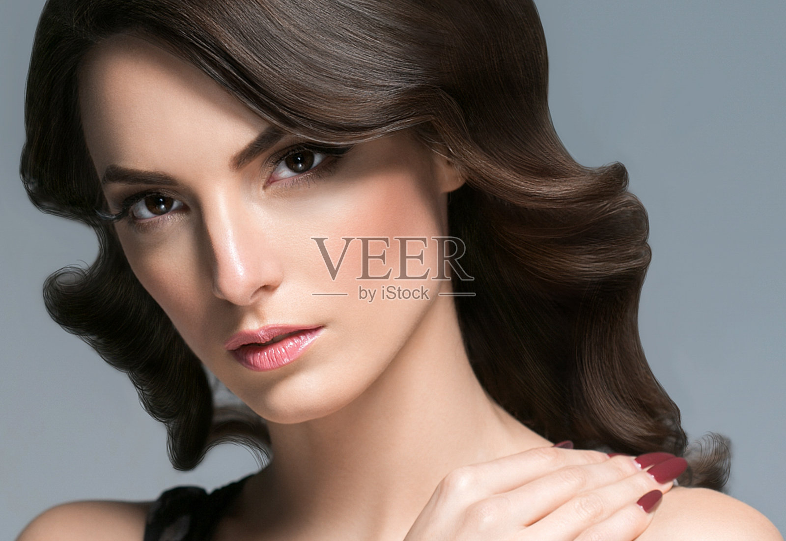 美丽的女人与卷发肖像在灰色的背景。女性年轻美丽的模特女孩的脸照片摄影图片