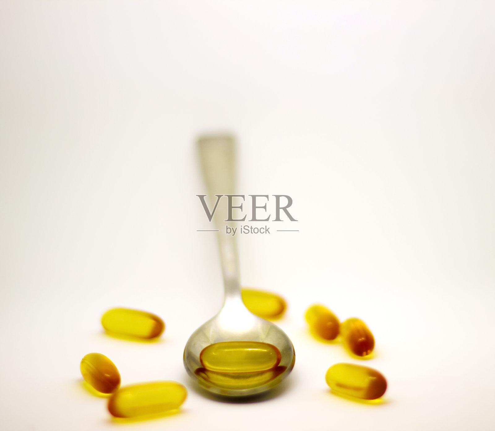 白色背景下的鳕鱼肝油Omega 3维生素E凝胶胶囊和钢勺照片摄影图片