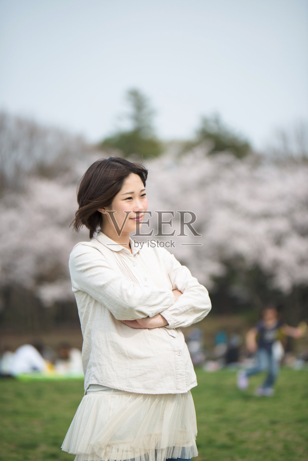 一位孕妇站在樱花树前照片摄影图片