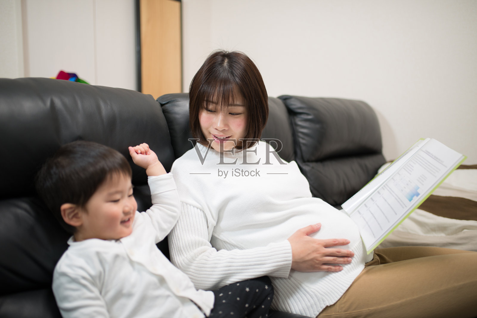 怀孕母亲在家工作与幼童照片摄影图片