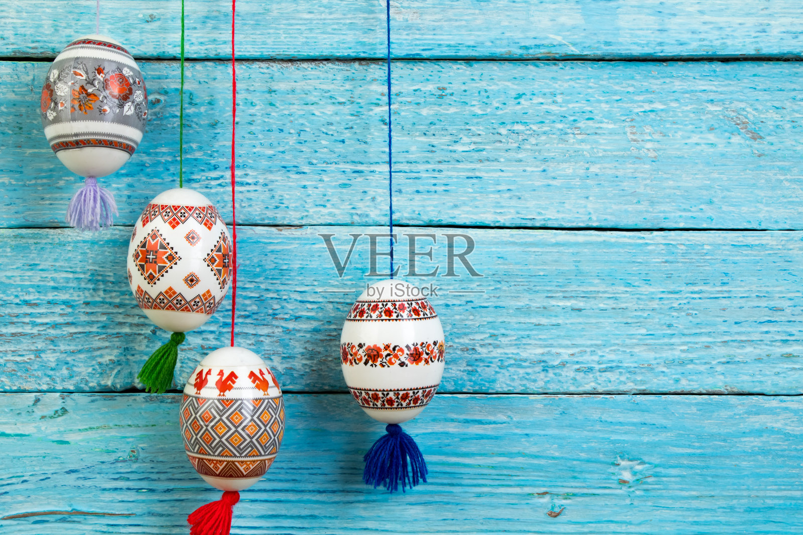 复活节快乐卡。在蓝色木制桌子的背景上，五颜六色闪亮的复活节彩蛋。文本复制空间照片摄影图片