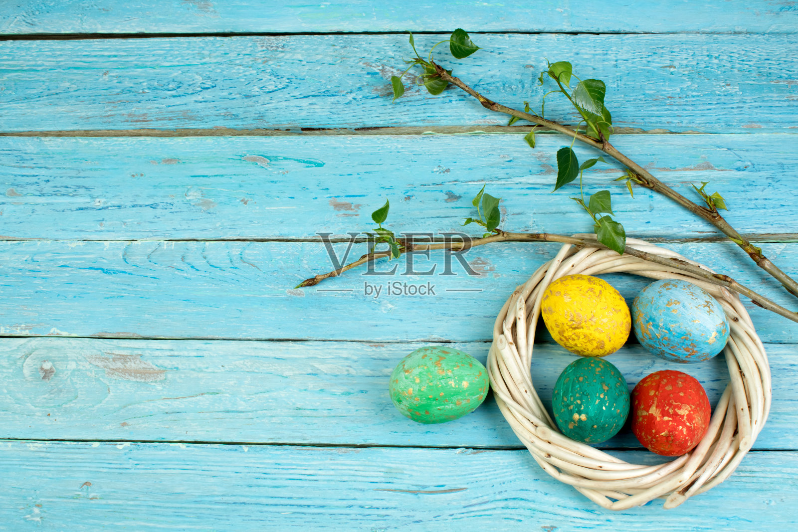 复活节彩蛋和带有树叶的树枝放在木桌的背景上。前视图。文本复制空间照片摄影图片