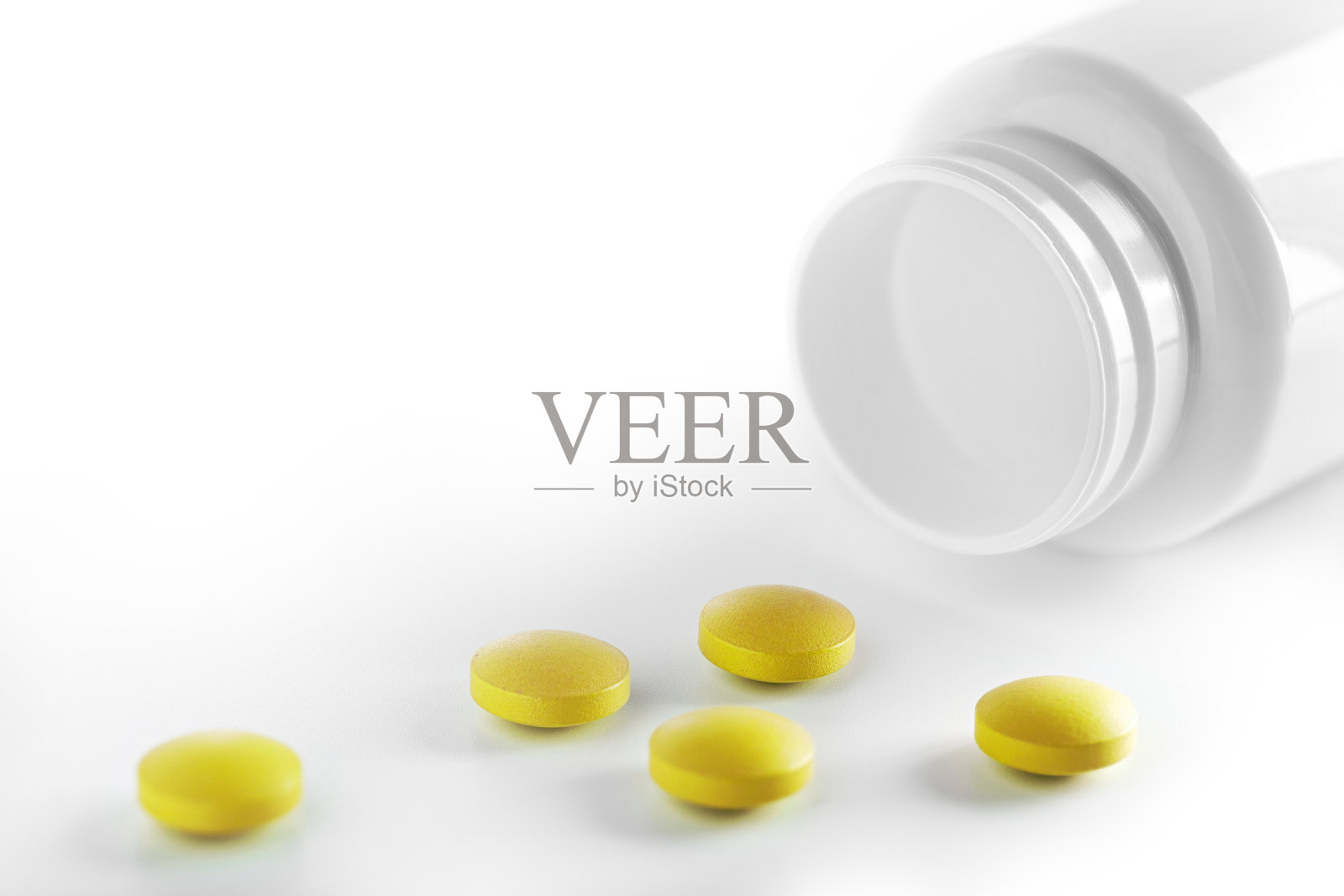 一堆黄色的药片和塑料白色的瓶子。药丸在白色的背景。保健和医学的概念。照片摄影图片