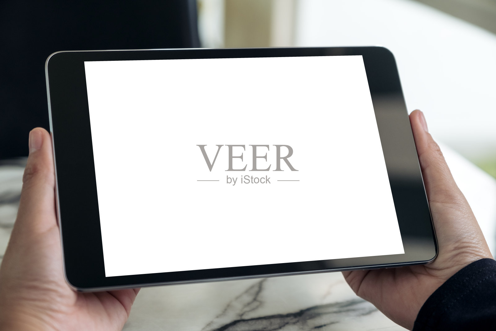 手握黑色平板电脑与空白的白色桌面屏幕在桌子上的模型图像照片摄影图片