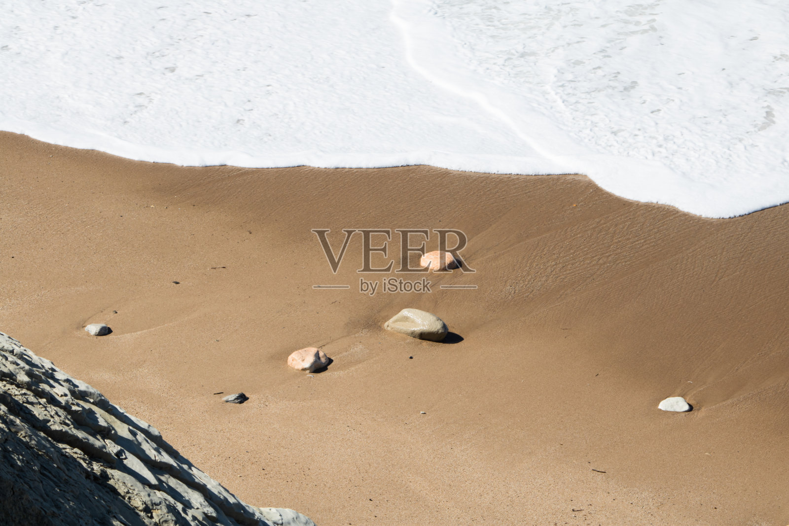 暑假在海滩上，靠近孤立的石头与海浪泡沫来海岸照片摄影图片