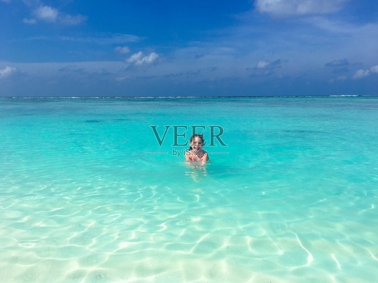 微笑的年轻女孩看着相机从海洋在热带岛屿上照片摄影图片