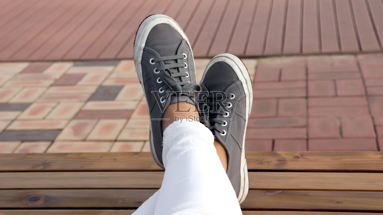 穿着灰色跑鞋的女人的两只脚。照片摄影图片