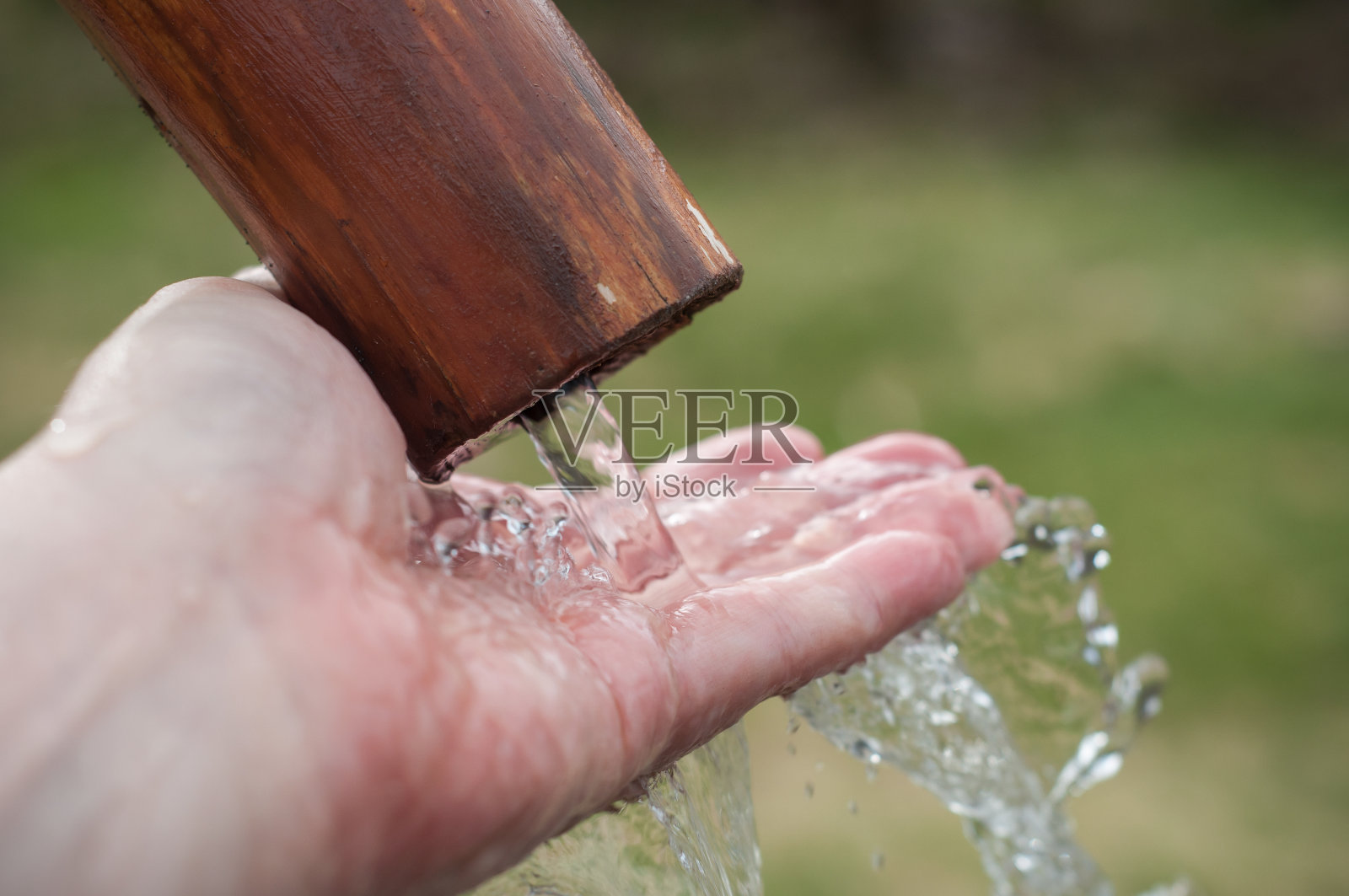 手在水中的典型木质喷泉，以山景为背景照片摄影图片