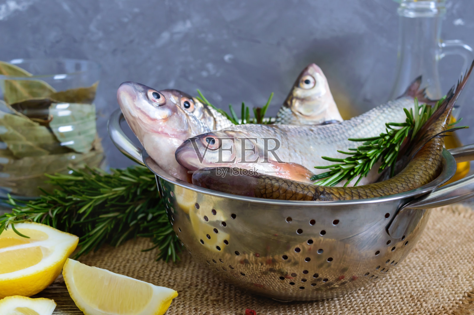 一堆新鲜的生鱼片，配上香料、柠檬和迷迭香，点缀在木质的背景上。新鲜捕获。照片摄影图片