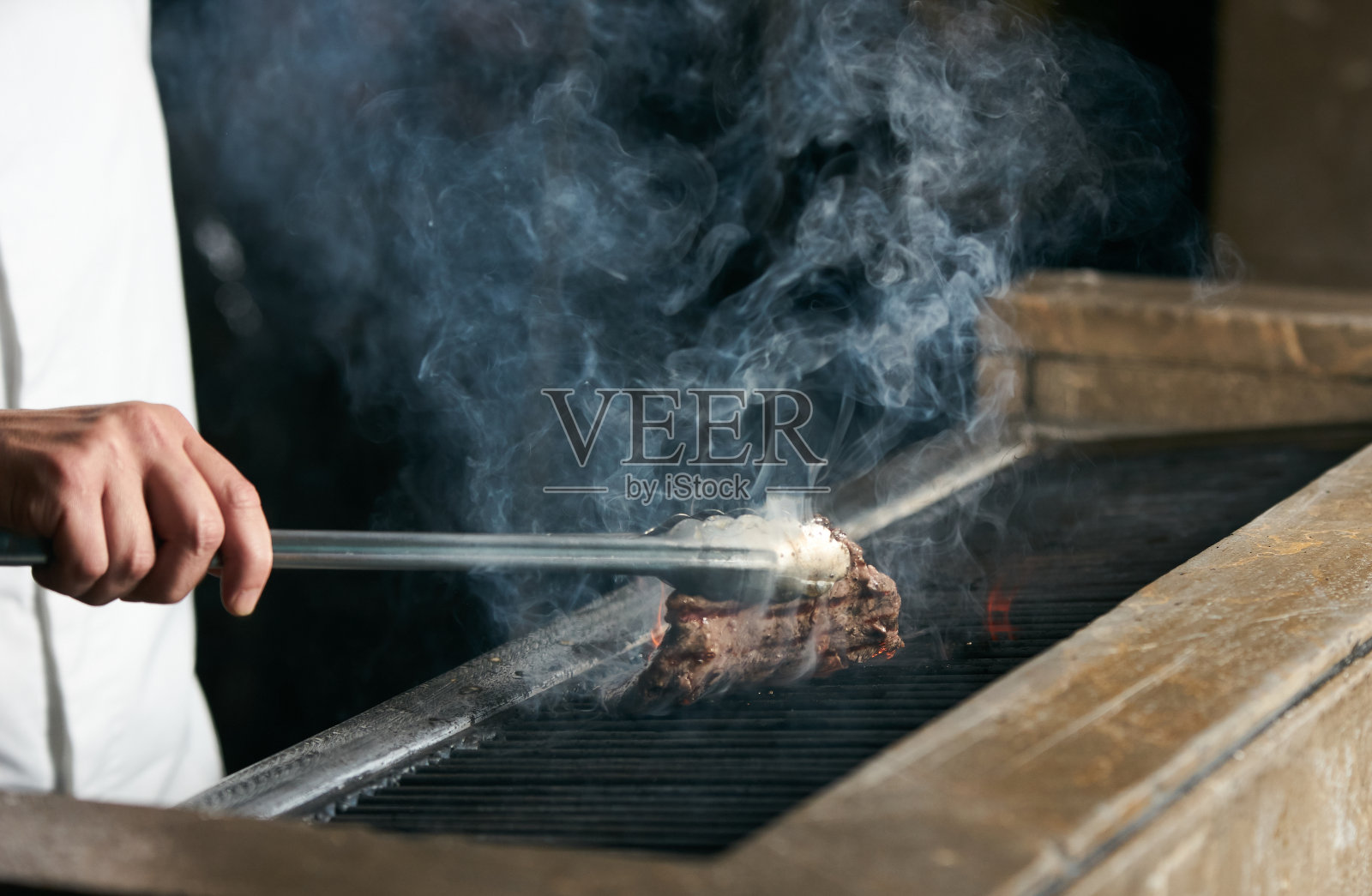 男人在烧烤架上烹饪牛排照片摄影图片