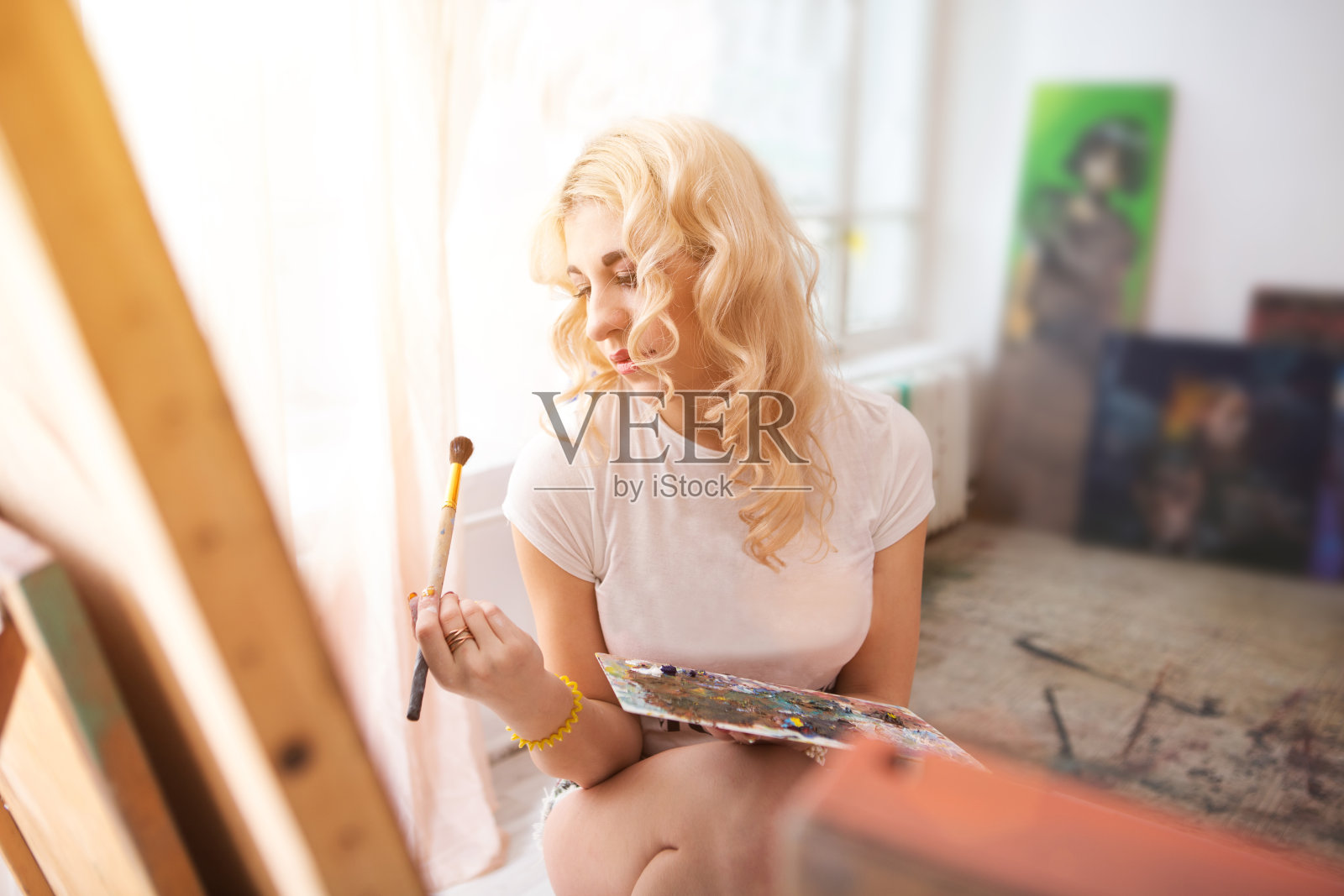 长发女子在她的画室里用油画颜料和画笔在画布上作画照片摄影图片