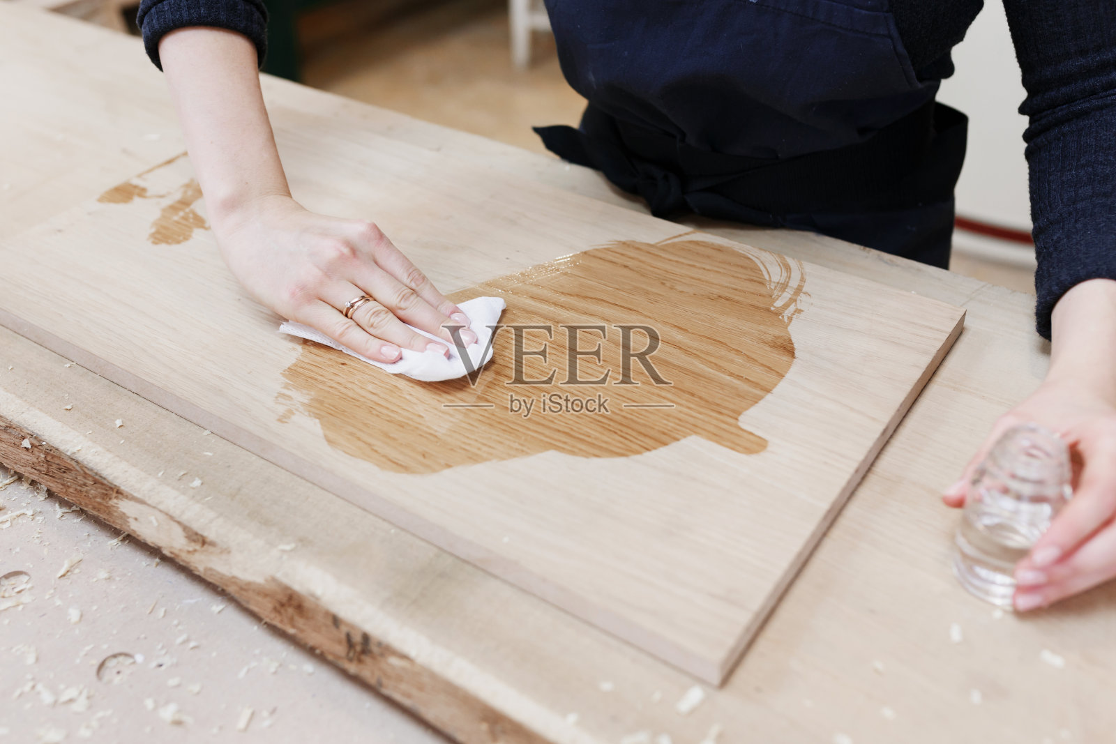 木材的油脂处理。女孩在一个木工车间工作，女性小企业照片摄影图片