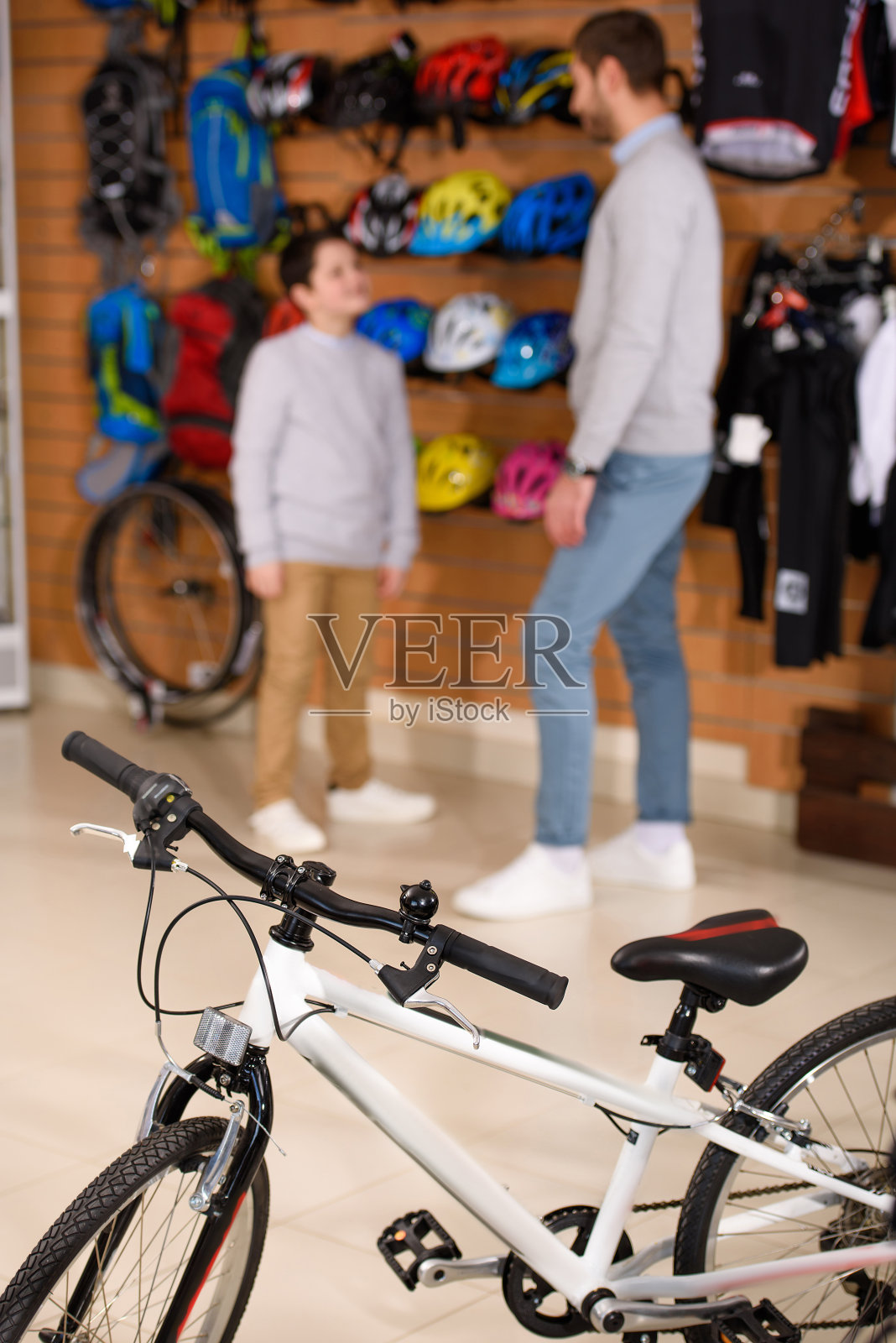 特写的新自行车和父亲与儿子站在后面在自行车店照片摄影图片