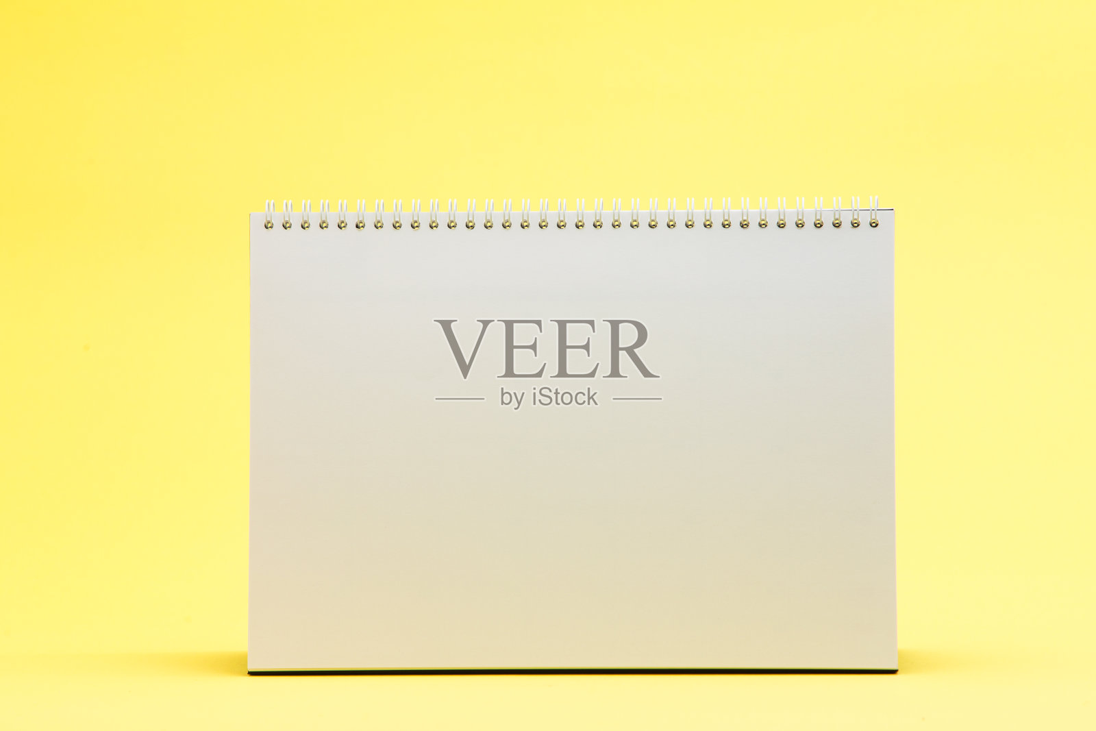 黄色背景上的空白白色台历照片摄影图片