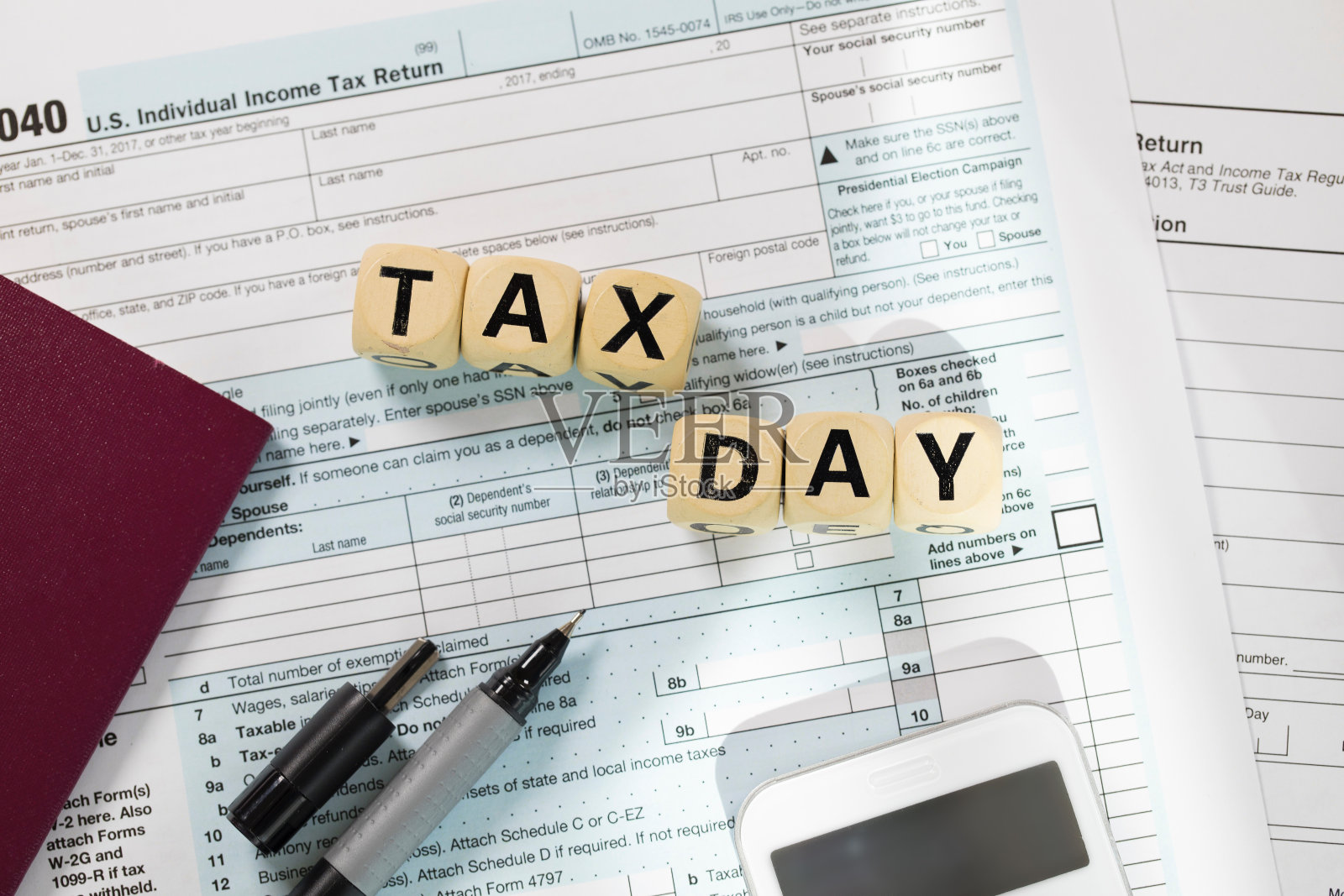 单词税务日由木制字母组成。钱，纸，笔在背后。照片摄影图片