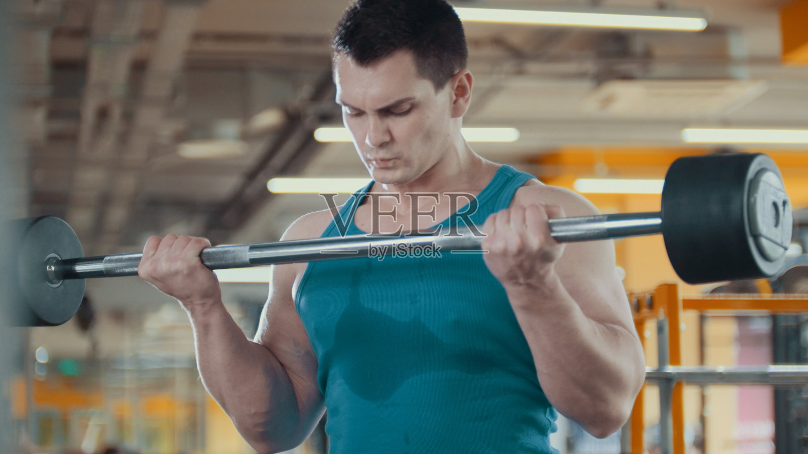 一个肌肉发达的英俊男子在健身房里举起了杠铃照片摄影图片