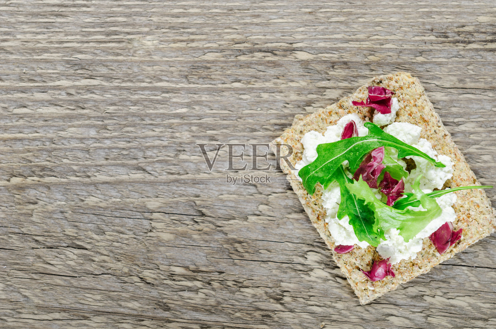 木桌上放着脆面包、软奶油奶酪和香草。顶视图、背景照片摄影图片