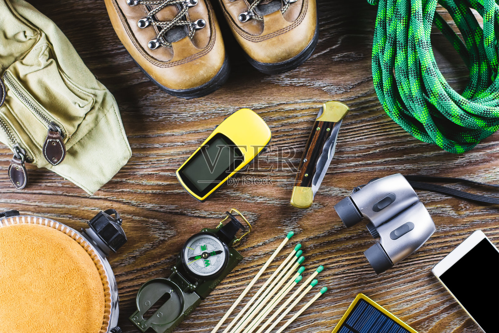 远足或旅行装备靴子，指南针，双筒望远镜，火柴在木制背景。积极的生活方式的概念。照片摄影图片