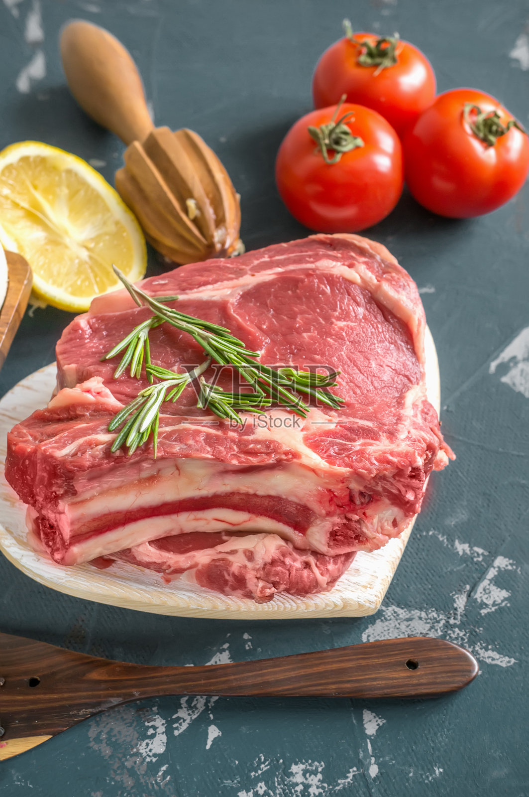 将切好的牛肉放在木砧板上烤，用月桂叶、迷迭香、橄榄油和普罗旺斯香草腌制，以一种乡村风格照片摄影图片