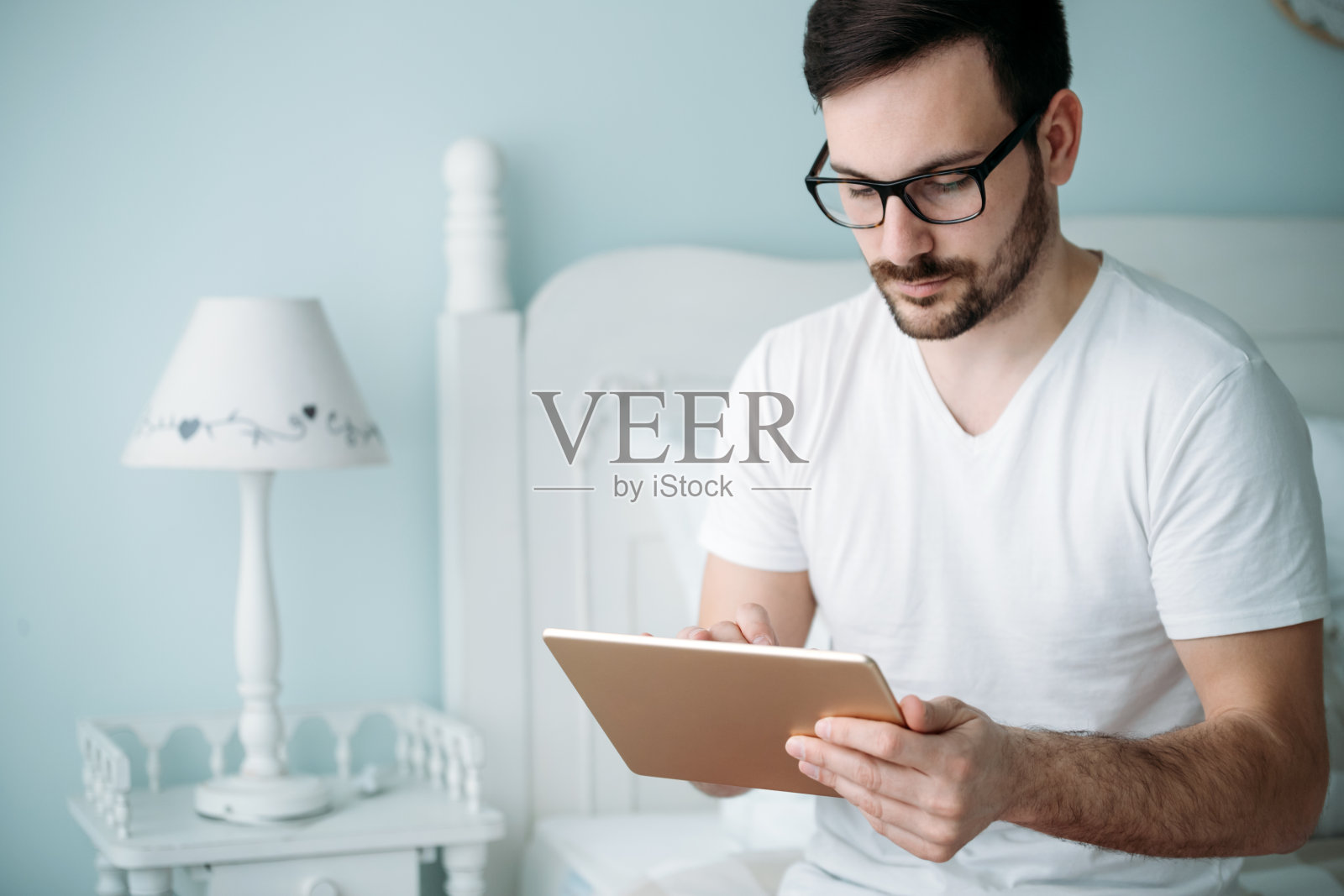 帅哥在卧室里用平板电脑照片摄影图片