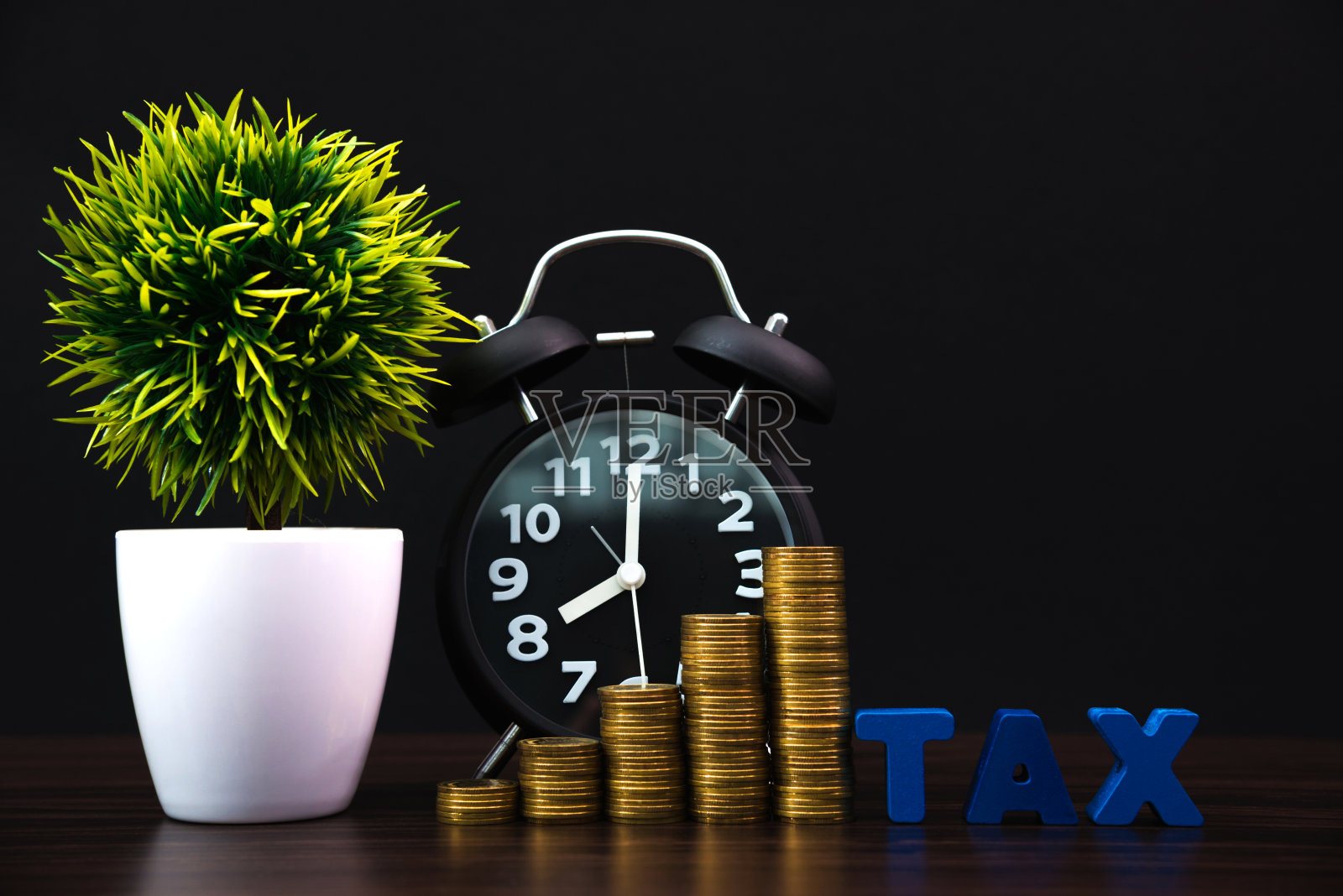 缴税时间概念。税务字母与堆栈硬币和古董闹钟在黑暗的背景，商业和金融概念。照片摄影图片