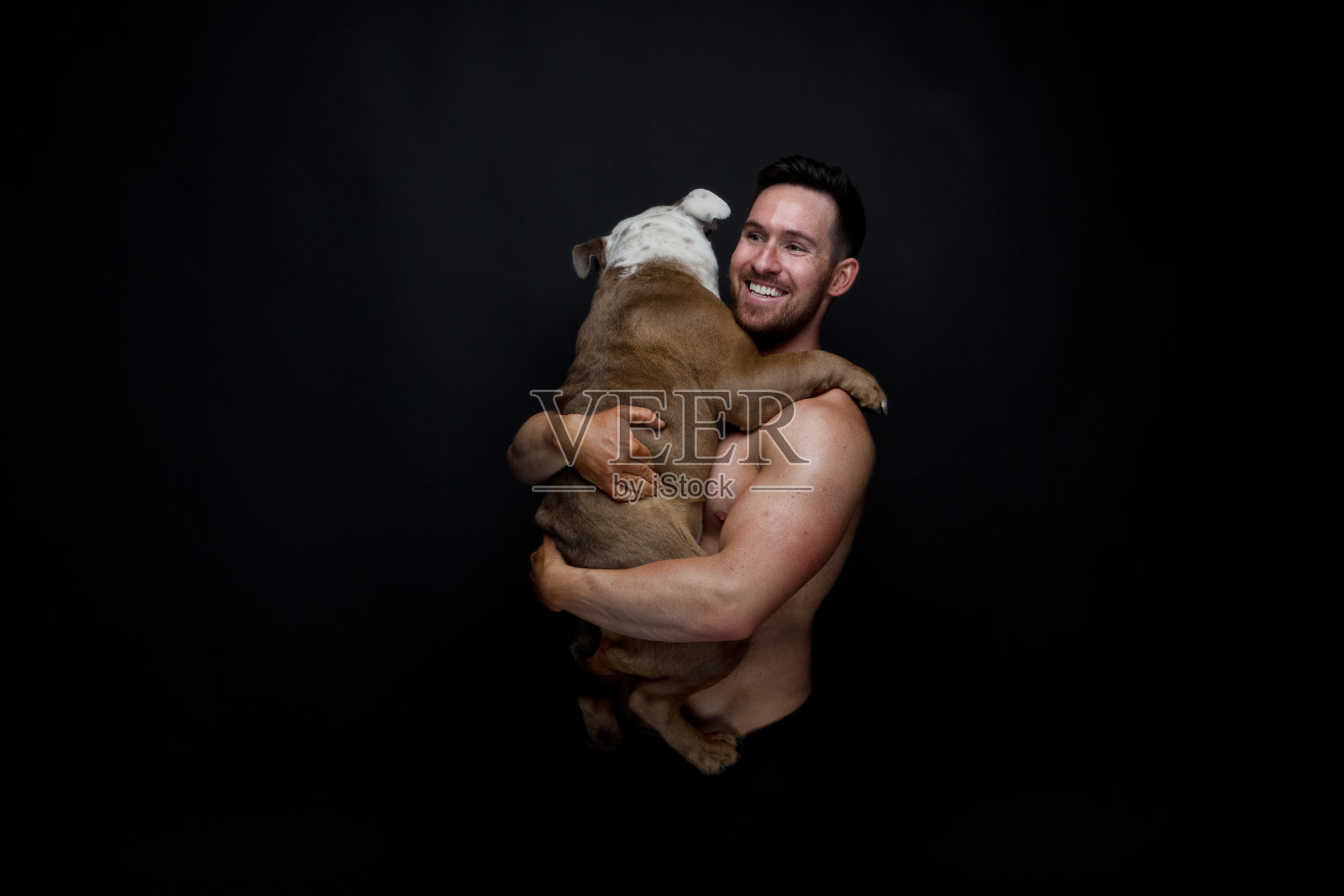 赤裸上身的男人牵着他的牛头犬照片摄影图片