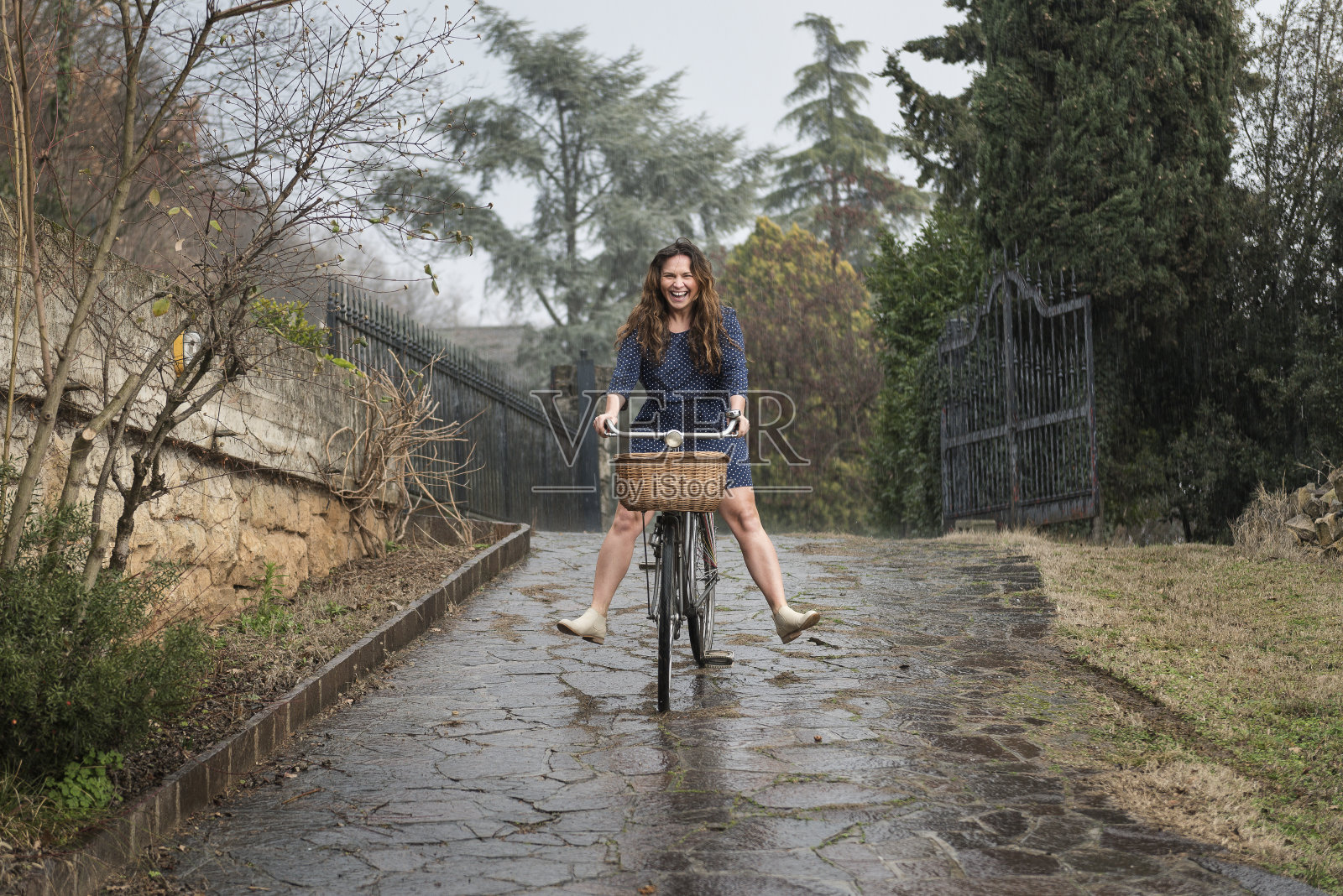雨中骑着自行车的女孩照片摄影图片
