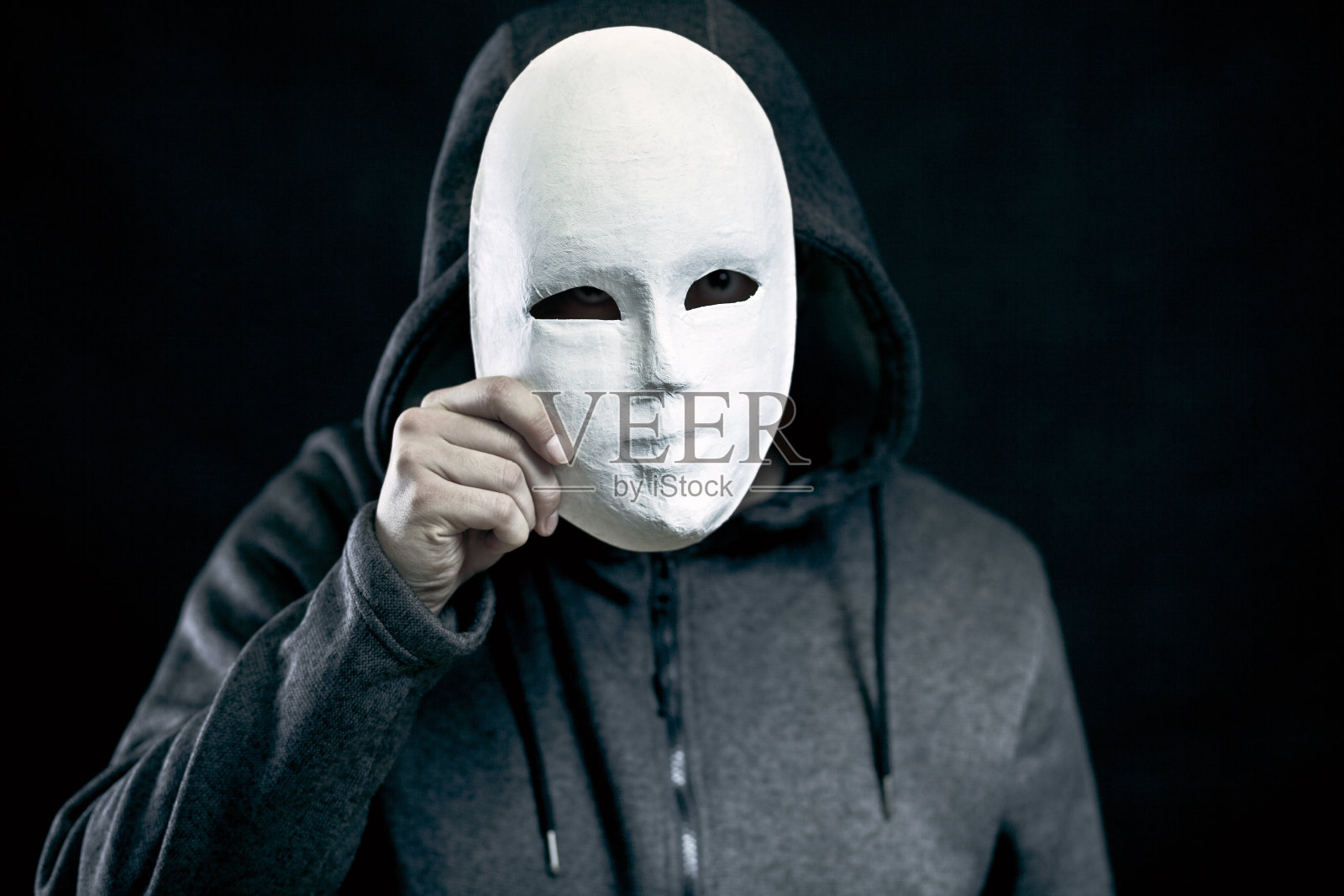 拿着白色面具遮脸的人照片摄影图片