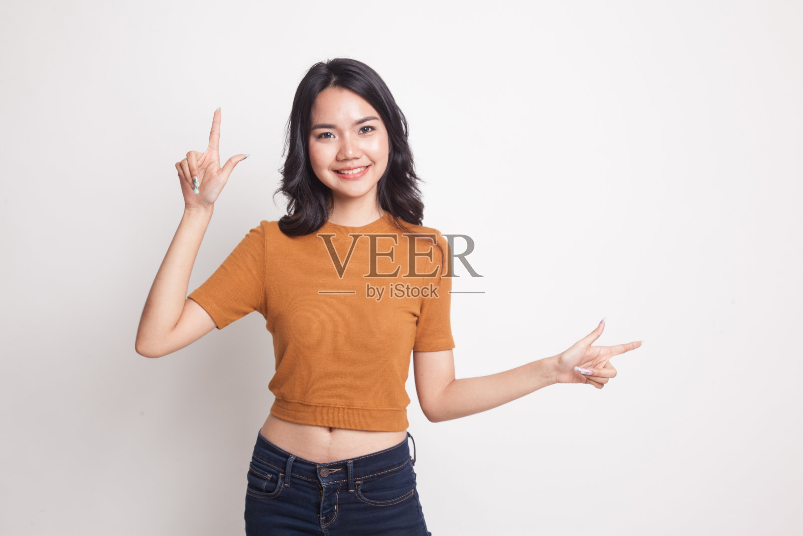 年轻的亚洲女子用两只手指着。照片摄影图片