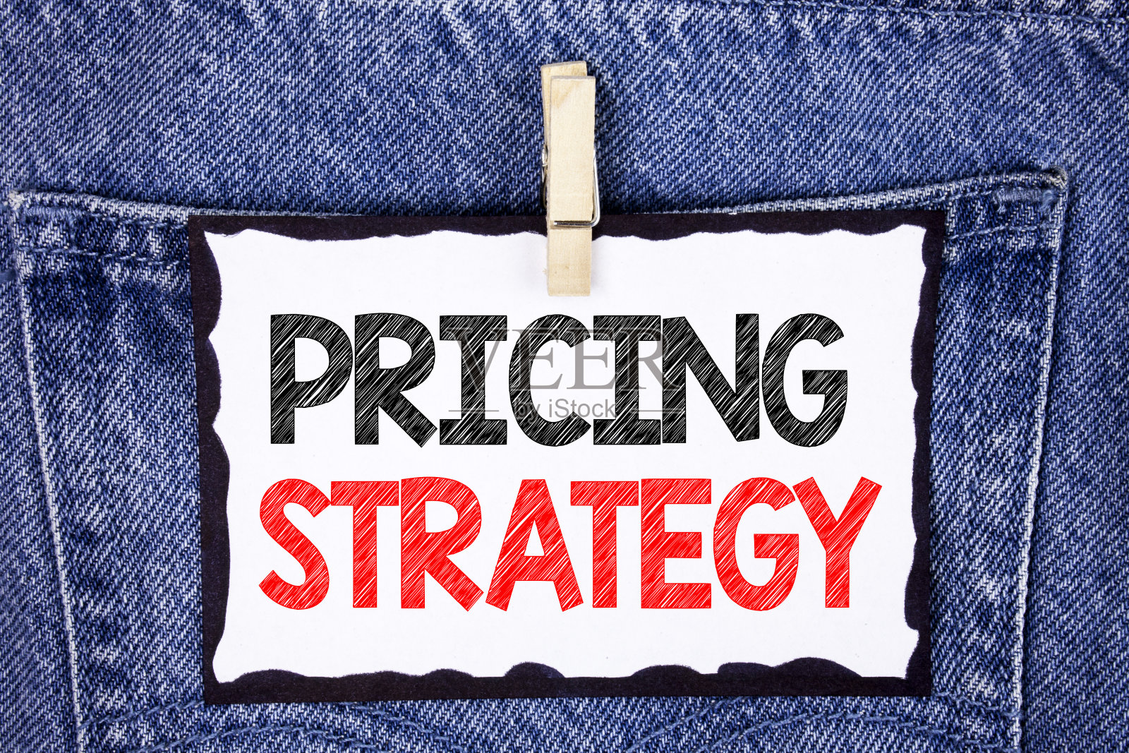 显示定价策略的文字标志。概念照片市场营销策略利润推广活动写在白色便签纸上，并把夹子挂在牛仔裤的背景上。照片摄影图片